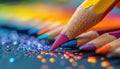 Close-up of a variety of colored pencils on a black background with a sprinkling of colorful glitter