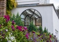 Close up of colourful flowers cascading down the front wall of a house overlooking the River Thames in Kew, London.