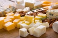 Close-up of various cheese cubes with almonds and knife on wooden board, copy space Royalty Free Stock Photo