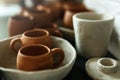A close-up of various drying clay tableware on a shelf. A pottery studio concept. Craftmade dishes, bowls, pots, mugs of