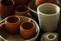 A close-up of various drying clay tableware on a shelf. A pottery studio concept. Craftmade dishes, bowls, pots, mugs of