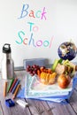 Close up of various school supplies and a lunch kit against a whiteboard. Back to school concept. Royalty Free Stock Photo