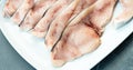 Close-up of various slices of raw swordfish, in a white plate, on a slate table..Tasty food from Italian cuisine and from the