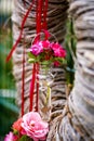 Close-up of a vase with pink flowers on a wreath next to a red ribbon. Decorative adornment