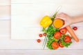 Close-up vegetables on a bright background. Woman holding a glass of juice. Healthful tomatoes and pepper on a wooden table. Royalty Free Stock Photo