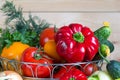 Close up vegetables harvest in wicker basket on wooden background. Red and yellow pepper, tomatoes, onion and green bow Royalty Free Stock Photo