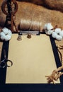 Close up vertical clipboard with vintage paper, beside cottons balls, rope and vintage spinning wheel. Mock up cotton template