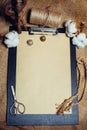 Close up vertical clipboard with vintage paper, beside cottons balls and vintage spinning wheel. Mock up cotton template.Top view