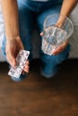 Close-up vertical cropped of unrecognizable young woman holding pills in hand with water. Female going to take tablet Royalty Free Stock Photo