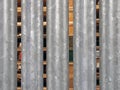 Close up of vertical galvanized steel fence with wooden pallets in outdoor storage visible between the gaps Royalty Free Stock Photo