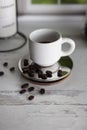 Close up vertical photo of coffee beans and a white ceramic espresso cup