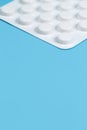 Close-up vertical photo white blister of pills on blue background. Medical, pharmacy and healthcare concept. Royalty Free Stock Photo