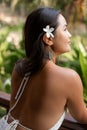 Close up vertical rearview captivating irresistible brunette woman with flower in hair striking pose, enjoying vacation Royalty Free Stock Photo