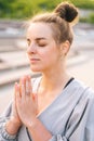 Close-up vertical shot of attractive young woman practicing yoga performing namaste pose with closed eyes outside in Royalty Free Stock Photo