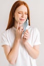 Close-up vertical shot of suffering young woman taking off disposable protective face mask, pointing finger to chin