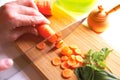 Close-up woman cutting carrots on wooden board, cooking food on table. Royalty Free Stock Photo