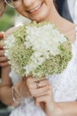 Close up vertical wedding bouquet of white and green field flowers in cropped unrecognizable smiling female bride hands