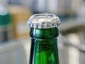 A close up of a vibrant green beer bottle being uncapped with a standard scale in the background Royalty Free Stock Photo