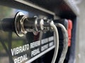 Close-up vibrato pedal input jack cable of a back control panel electric guitar amplifier with blurred grey cement background. Royalty Free Stock Photo