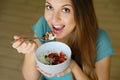 Close up view from above of beautiful young woman eating skyr with cereal muesli fruit and seeds at home, focus on model eyes Royalty Free Stock Photo