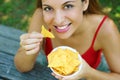 Close up view from above of beautiful young woman eating tortilla chips outdoor