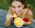 Close up view from above of beautiful young woman eating tortilla chips outdoor