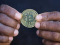 Adult afro man holding bitcoin coin in black skin hands