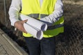 Close up view of Architect or Engineer man holding blueprints on the Construction Site. Wearing protection clothes. Crane on Royalty Free Stock Photo