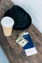 close up view of arranged passport, cash, coffee to go and hat