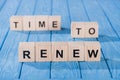 close up view of arranged wooden blocks into time to renew phrase on blue wooden surface