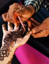 View of artist drawing Indian henna or herbal way of traditional temporary tattooing on a womans hand