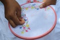 Close up view of an asian woman sewing a hand embroidery using a needle and red thread