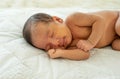 Close up view of Asian young newborn baby is sleeping and smile on white bed in the bedroom with soft light Royalty Free Stock Photo