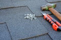 Close up view on asphalt bitumen shingles on a roof with hammer,nails and stationery knife background Royalty Free Stock Photo