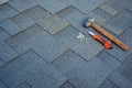 Close up view on asphalt bitumen shingles on a roof with hammer,nails and stationery knife background.