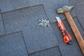 Close up view on asphalt bitumen shingles on a roof with hammer,nails and stationery knife background. Royalty Free Stock Photo