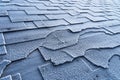 Close up view on Asphalt Roofing Shingles roof damage covered with frost. Royalty Free Stock Photo