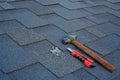 Close up view on asphalt shingles on a roof with hammer,nails and stationery knife background