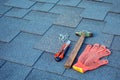 Close up view on asphalt shingles on a roof with hammer,nails and stationery knife. Royalty Free Stock Photo