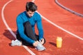 Close up view, of an athlete tying his shoe laces. Man tightening his shoe laces sitting on the ground on a running Royalty Free Stock Photo