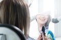 Close-up view from the back of a blonde girl sitting in a chair who looks in a tooth-shaped mirror. Reflection of a snow Royalty Free Stock Photo