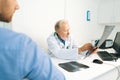 Close-up view from back of young male patient listening mature adult doctor explaining results of MRI scanning, giving Royalty Free Stock Photo