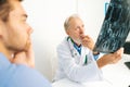 Close-up view from back of young male patient listening mature adult doctor explaining results of MRI scanning, giving Royalty Free Stock Photo