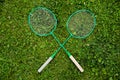 Badminton rackets laying on green grass crossed as x, outdoors, Copy text space