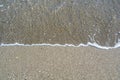 Close up view of beach with a sea wave, small stones, sand and shells