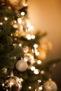 Close up view of beautiful fir branches with shiny golden bauble or ball, xmas ornaments and lights, Christmas holidays Royalty Free Stock Photo