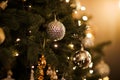 Close up view of beautiful fir branches with shiny golden bauble or ball, xmas ornaments and lights, Christmas holidays Royalty Free Stock Photo