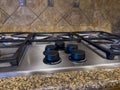 Close up view of a beautiful gas stove top with black knobs against a square tiled backsplash Royalty Free Stock Photo