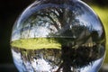 Close up view on beautiful landscape trees in blue sky and green meadow through lens ball sphere, france Royalty Free Stock Photo