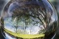 Close up view on beautiful landscape trees in blue sky and green meadow through lens ball sphere, france Royalty Free Stock Photo